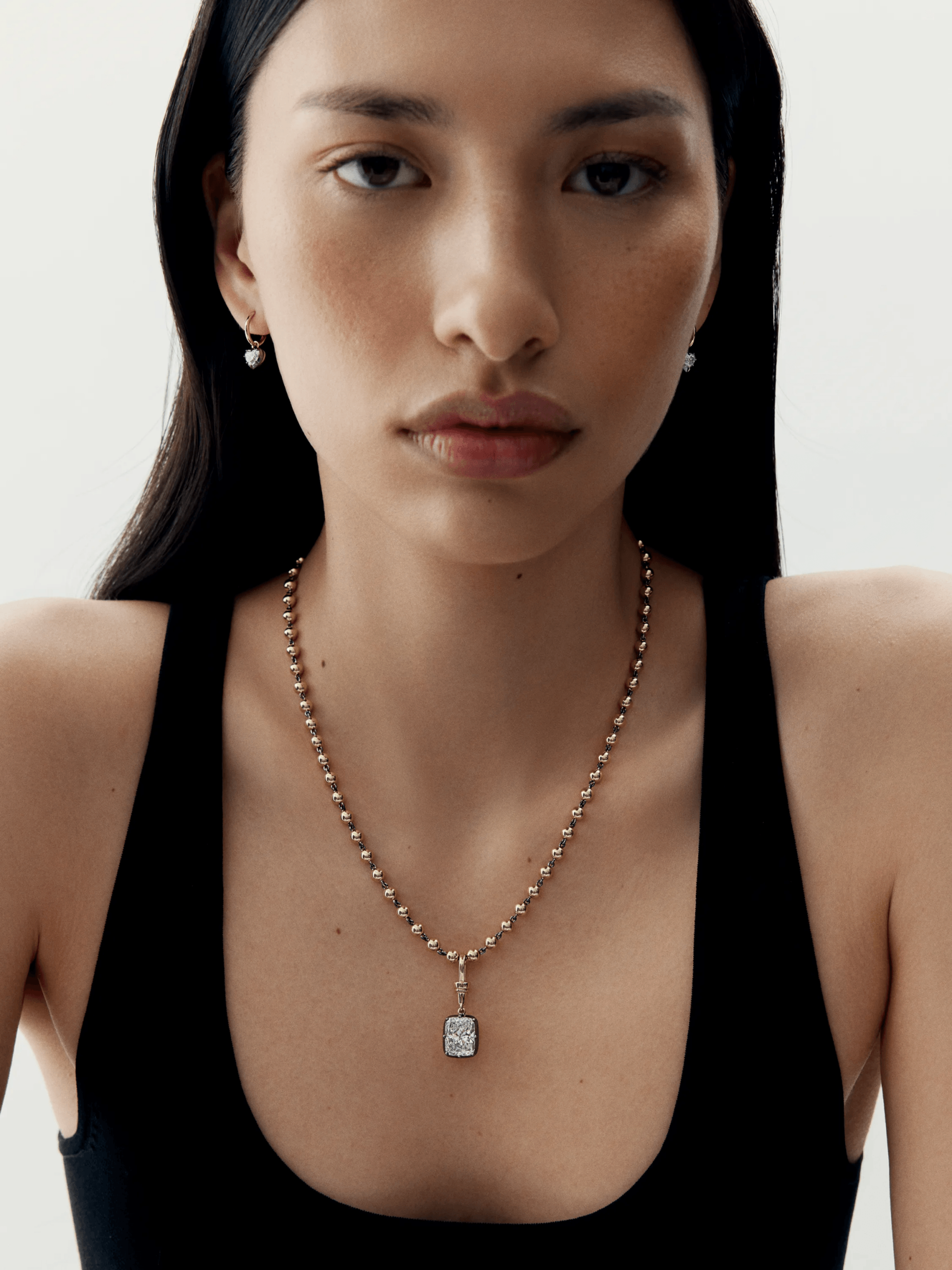 Close-up of a woman wearing an antique-inspired gold necklace with a cushion-cut diamond pendant and matching delicate diamond earrings, showcasing expert craftsmanship. View 3