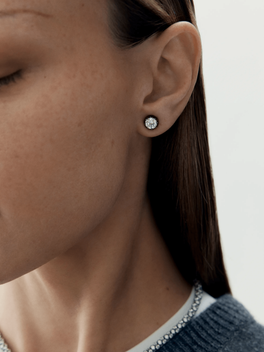 Close-up of a woman's ear wearing a 1ct diamond stud earring set in blackened gold, showcasing a blend of antique-inspired craftsmanship and contemporary design.