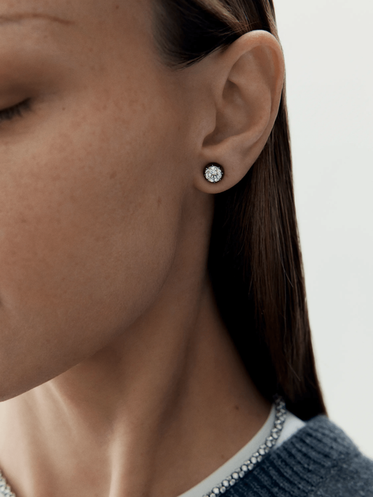 Close-up of a woman's ear wearing a 1ct diamond stud earring set in blackened gold, showcasing a blend of antique-inspired craftsmanship and contemporary design. View 3