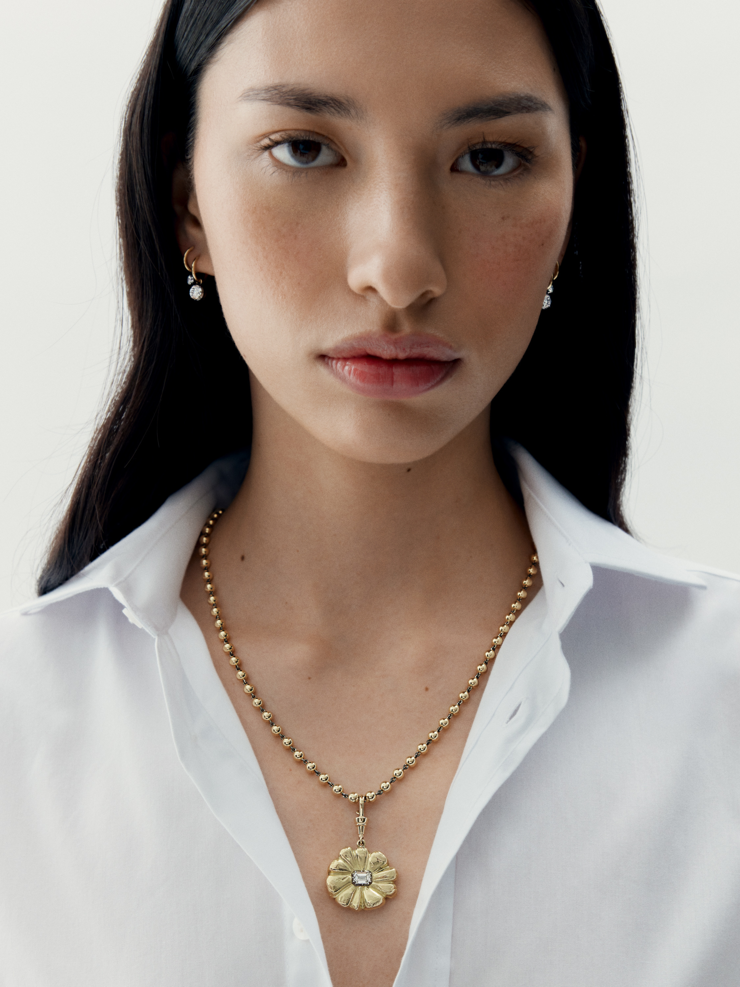 Woman wearing a gold necklace with a pendant against a white background View 3