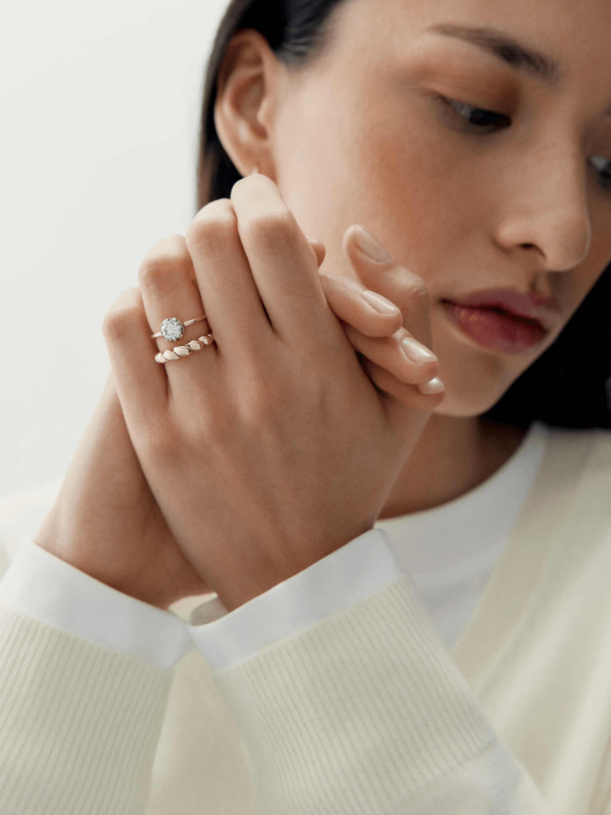 Close-up of a woman's hands gently clasped, featuring a contemporary white gold ring with a 0.90ct diamond, showcasing refined craftsmanship and elegant design. View 3