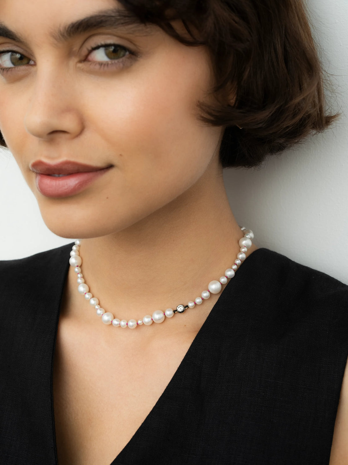 Jessica McCormack pearl necklace with a 0.40ct diamond detail on pink thread, worn close to the neck with a black sleeveless top View 3
