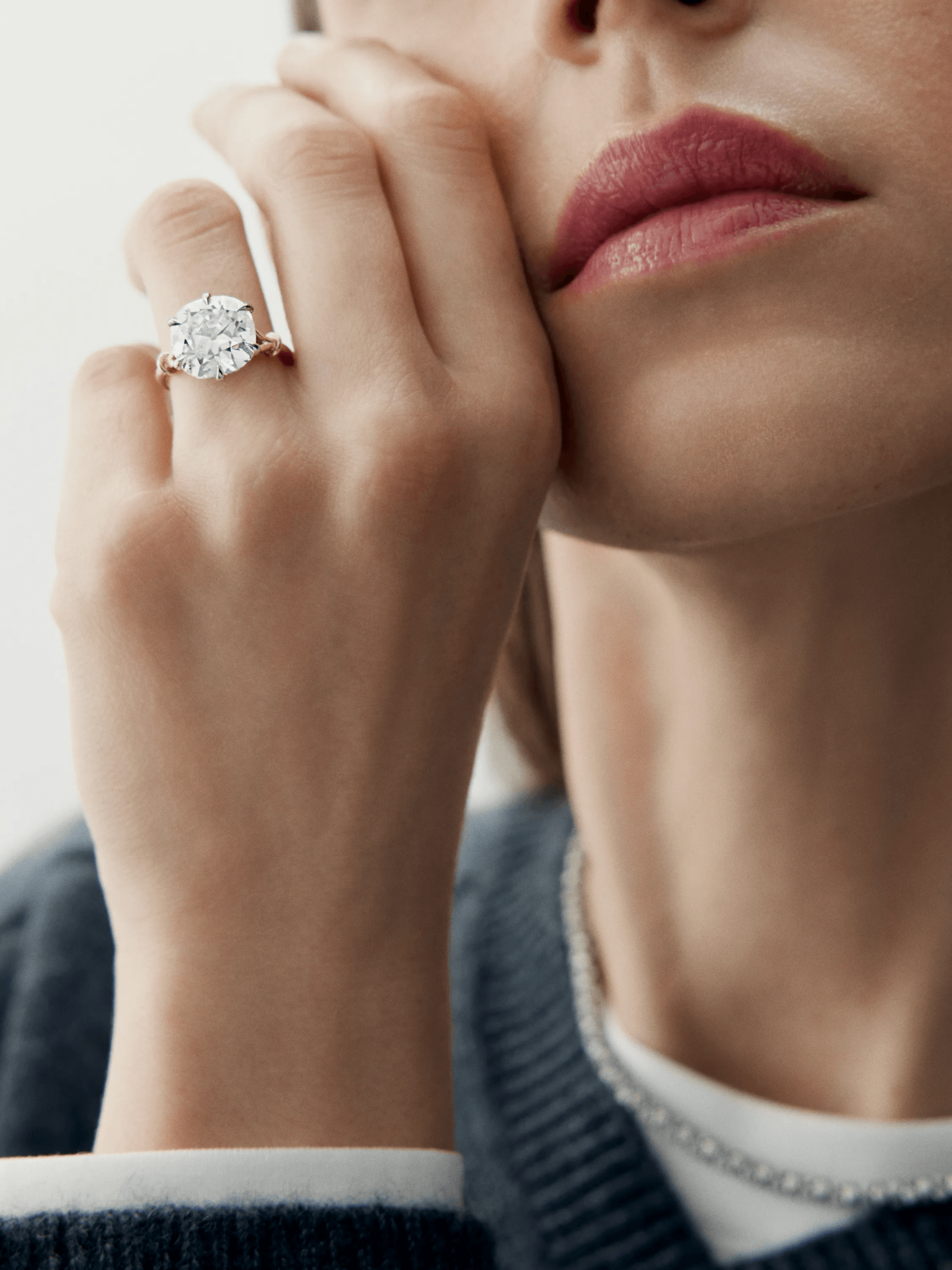 Close-up of a woman wearing a cushion-cut diamond ring with a delicate, antique-inspired platinum or white gold band, highlighting fine craftsmanship and timeless elegance. View 3