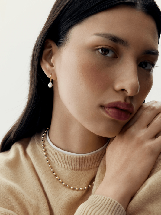 Close-up of a woman wearing contemporary white gold hoop earrings set with pear-shaped diamonds, highlighting timeless craftsmanship and elegant gypset style. View 3