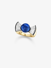 Yellow gold ring with a round blue sapphire centre and fan-shaped diamond accents, showcasing contemporary style and traditional craft techniques.