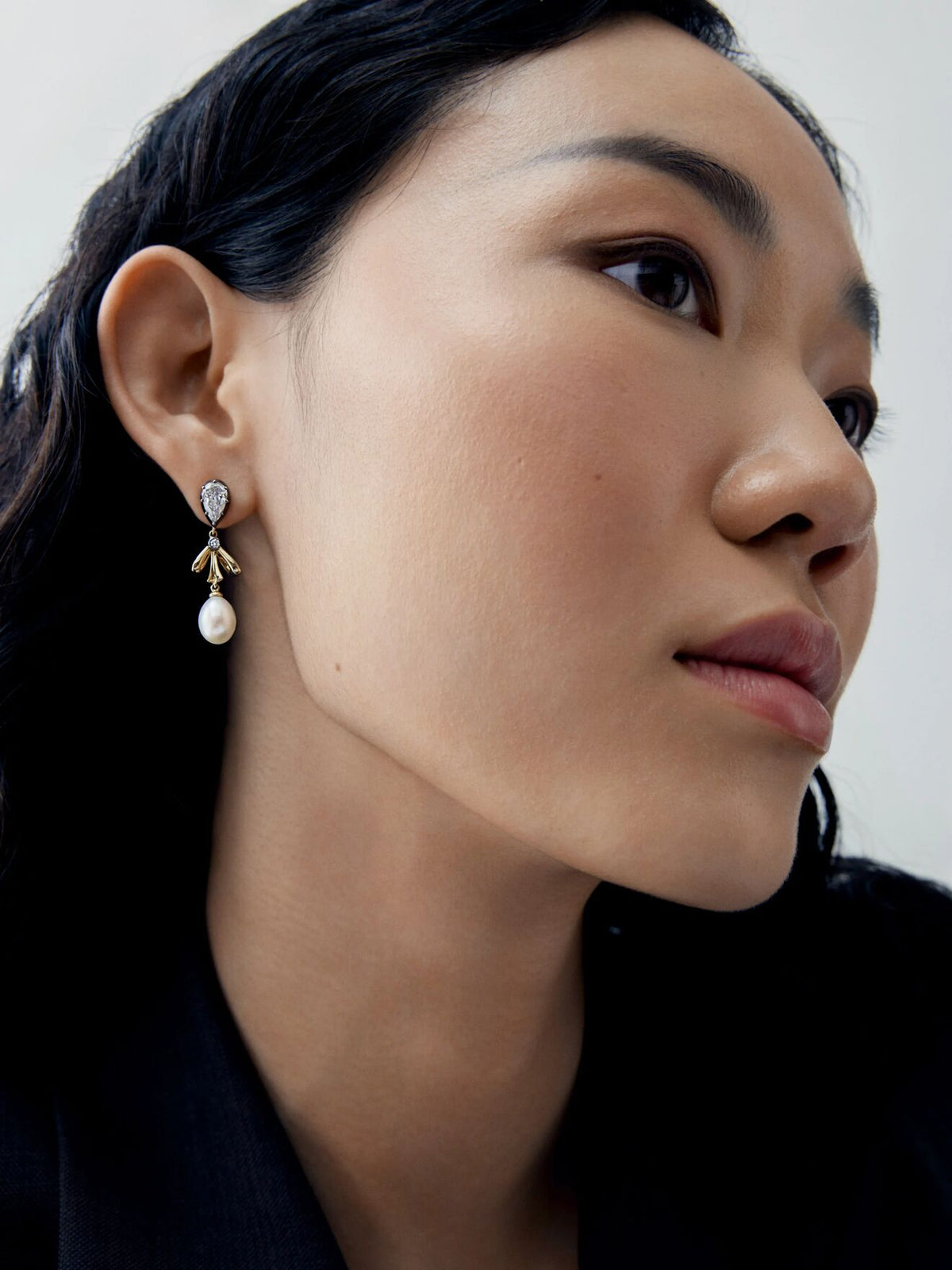 Close up portrait of a model wearing a diamond, gold and pearl bow drop earring, showcasing Jessica McCormack's antique inspired contemporary style View 3