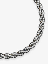 Close-up of a Jessica McCormack diamond and blackened gold necklace with intertwined ribbon links and rows of round diamonds in a sculptural design