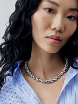 Diamond and blackened gold ribbon necklace worn with a blue striped blouse, showcasing Jessica McCormack craftsmanship and contemporary style