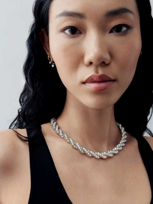Model wearing a diamond and white gold ribbon necklace with an intricate bow-inspired design, showcasing contemporary style and traditional craft techniques View 3
