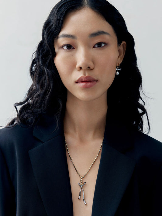 Portrait of a woman wearing a diamond bow pendant on a delicate ball n chain necklace, styled with a contemporary black blazer View 3