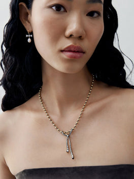 Jessica McCormack diamond ribbon pendant necklace worn on a model, featuring a delicate beaded chain and two slender drop ends.