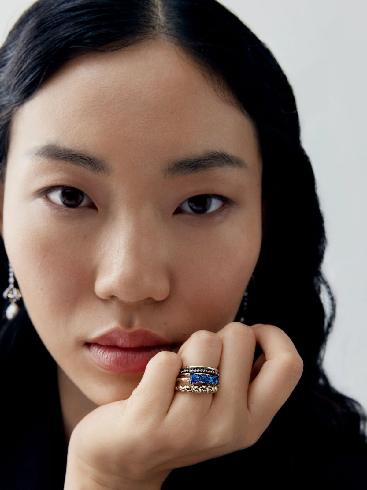Close-up portrait of a woman wearing a blue sapphire ring with diamond accents, showcasing contemporary style and refined craftsmanship View 3