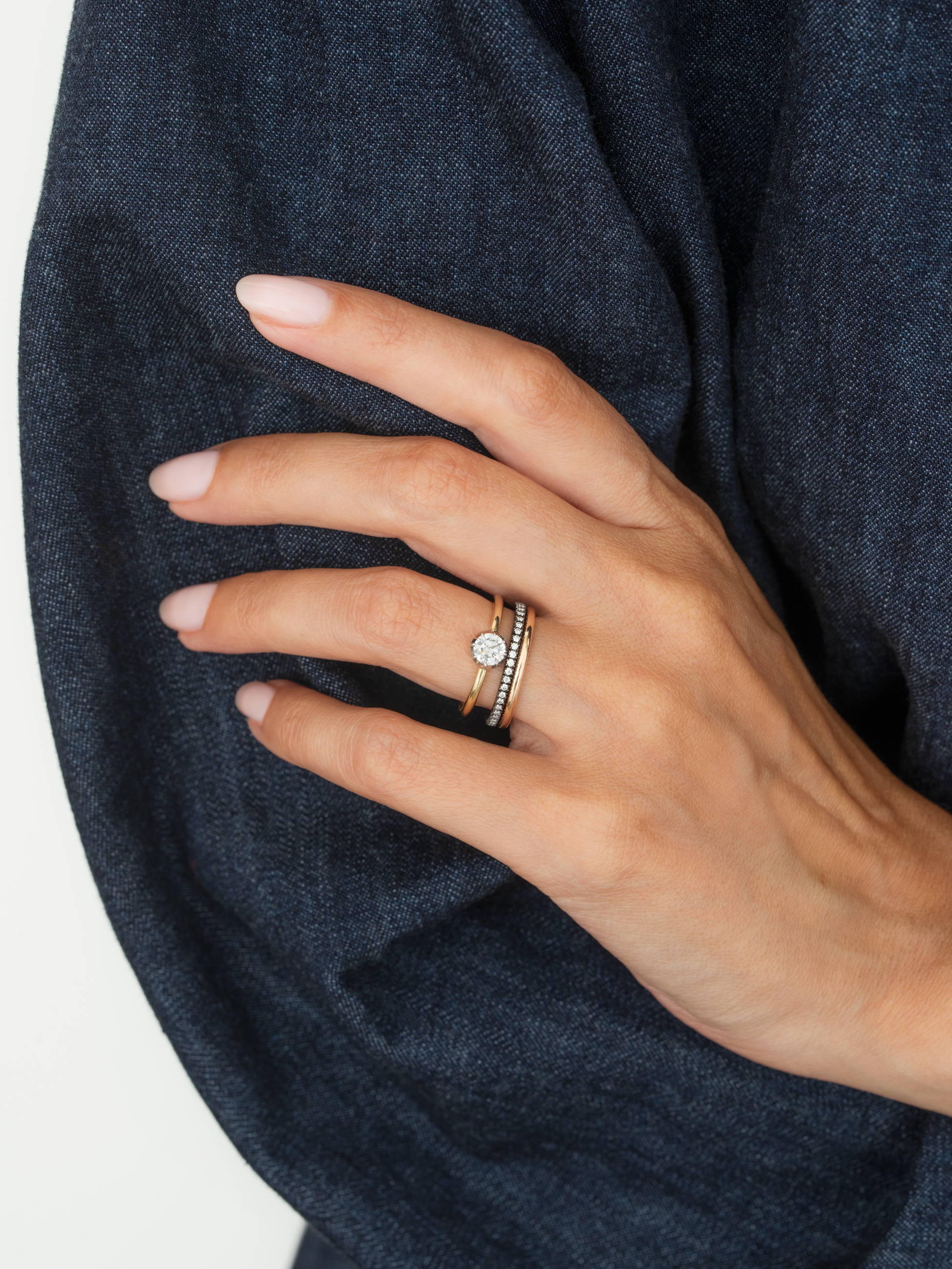 Close-up of a hand wearing a 0.50ct diamond white gold button back ring paired with a slim diamond band, showcasing contemporary craftsmanship and elegant design. View 3