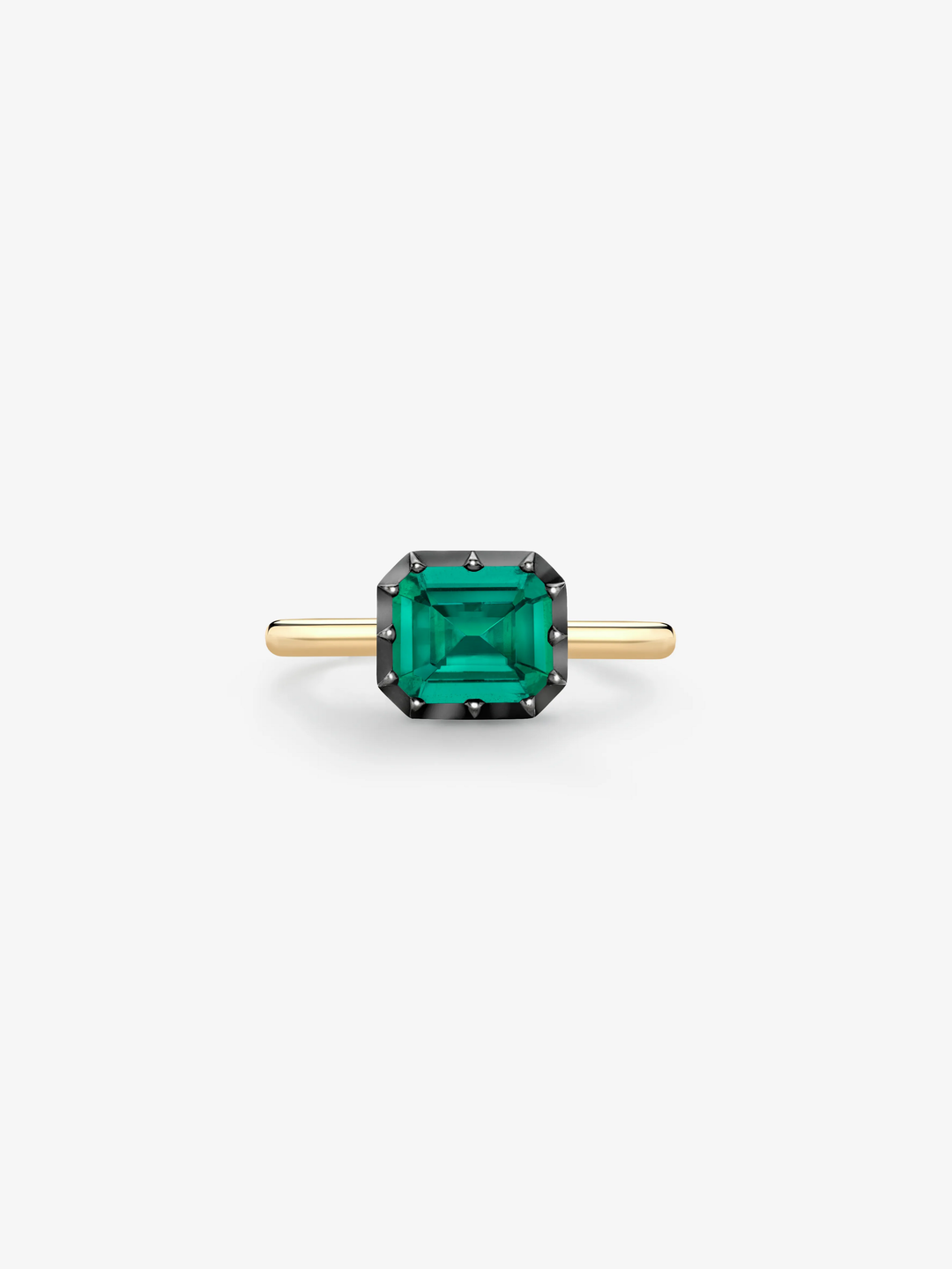 Elegant ring featuring a vibrant emerald-cut green emerald set in a blackened gold bezel with a sleek 18K yellow gold band, blending antique charm with modern design.  View 1