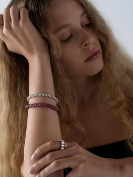 Close-up of a woman wearing a vibrant ruby bracelet paired with a diamond bracelet, showcasing expert craftsmanship in a contemporary antique-inspired style.
